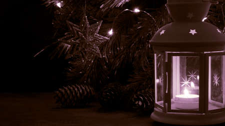 White lantern with a burning candle. Pine branch and blurred lights on background. Night dark picture. Christmas mystery mood.の写真素材