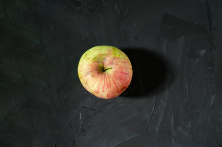 The single apple in the middle of the dark gray background. Red and yellow ripe apple. Concrete background.の写真素材