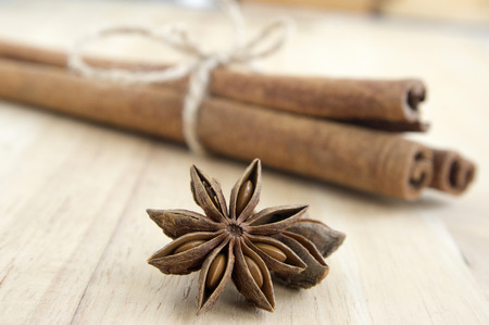 Fresh raw cinnamon sticks tied with natural twine and star anise on wooden tableの写真素材