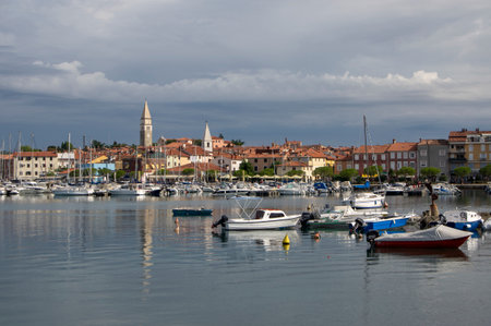 Izola / SLOVENIA - September 8, 2019: Touristic view of Izola old fishing town historic center with church tower and marina with boats in the foregroundのeditorial素材