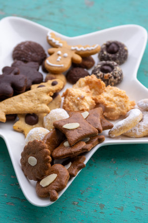 Decorated traditional Christmas gingerbread arranged on white plate star shaped in daylight, various cookiesの写真素材
