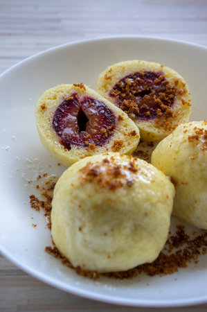 Sweet plum dumplings on a white plate, with white sugar icing and grated gingerbread, delicious Czech cuisine foodの写真素材