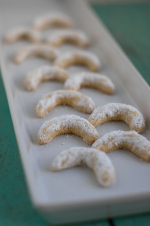 Vanillekipferl typical Czech sweet Christmas baking cookies, vanilla rolls crescent moon with white icing on long plate in rowsの写真素材