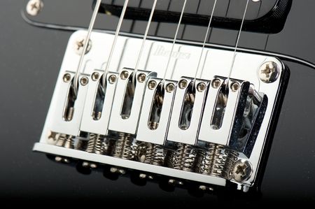 bridge detail of black e-guitar photographed in studio