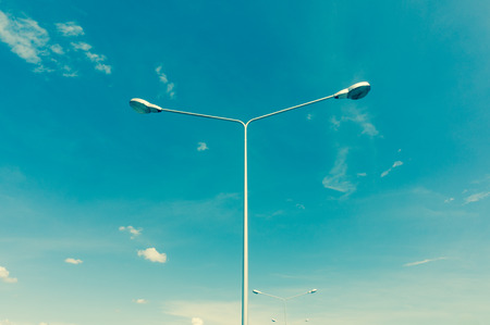 street lamps aligned with blue sky in background, cross process style
