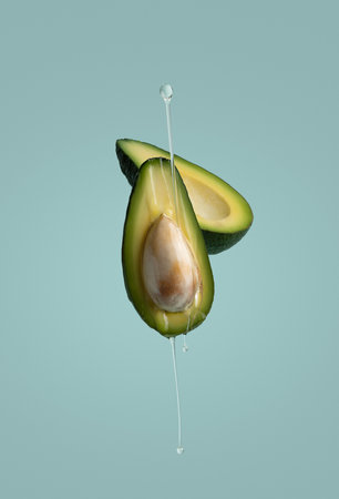 Fresh two beautiful avocados cut in half and poured with olive, flowing avocados on a beautiful uniform background, a beautiful picture for advertising or restaurant. Isolated avocの写真素材
