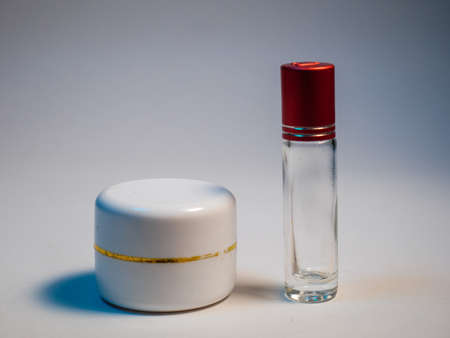 Cosmetic bottle with red cap on a white background.の写真素材