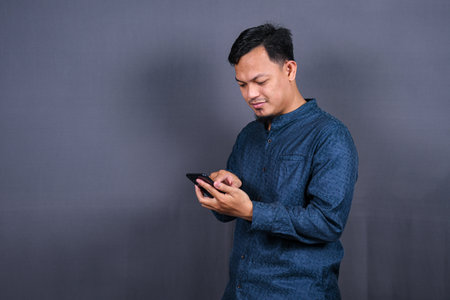 Happy asian man typing sms on gray background. isolated, business conceptの写真素材