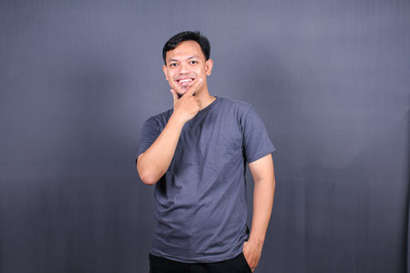 Young asian man thinking about things, isolated on gray background. Mockup copyspaceの写真素材