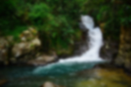 Blurred view of waterfall in the stream with rocks in the forest
