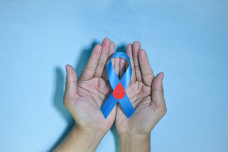 Top View Blue ribbon awareness with red blood drop in man hands isolated on a blue background. 14 november, World diabetes day. Copyspaceの写真素材