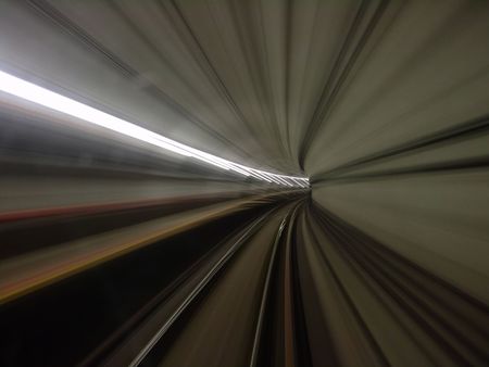 view of lighted tunnel at a turning from a fast moving train