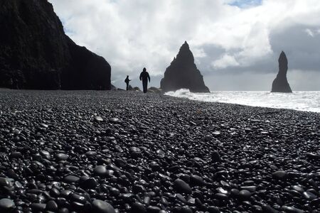 Reynisfjara - famous black beach with interesting rock formations on South Iceland and walking touristsの写真素材