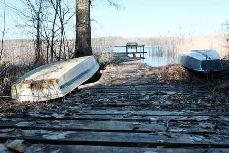 Boats on the shore of the Trzechowskie Lake and a wooden bridge among the rushes, Bory Tucholskie, Polandの写真素材