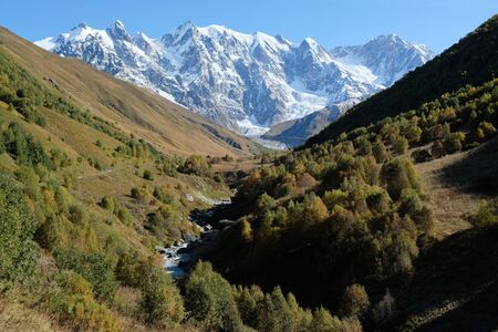 Snowy peak Dzhangi-Tau and Shkhara with Khalde Glacier, with green mountainsides and Khaldechala...