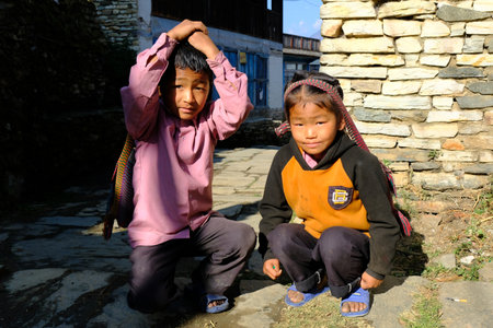 Nepal, Himalayan village around Annapurna - circa October 2019: Two Nepali little boys with traditional headbands. Meeting on trail during trekking around Annapurna, Annapurna Circuit trail.のeditorial素材