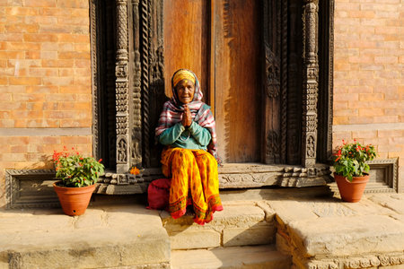 Bhaktapur, Nepal - circa November 2019: Hindu holy woman in traditional colorful dress at entrance of Palace of Fifty-five Windows at Durbar Square, Bhaktapur, Nepalのeditorial素材