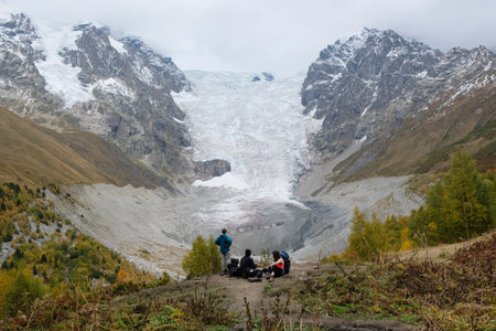 Group of tourist on viewpoint in colorful autumn place with Adishi Glacier in background in misty day. During trekking on trail from Khalde to Mulakhi in Greater Caucasus, Georgia.のeditorial素材