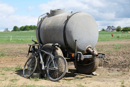 A small old tanker stands in the field and a bicycle leaning on it. In the distance you can see the village buildings. Polish countryside, Cracow-Czestochowa Upland, Poland.のeditorial素材