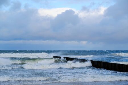 Waves crashing against a breakwater on a stormy day on the beach in Dziwnowek / Poland on the Baltic Seaの写真素材