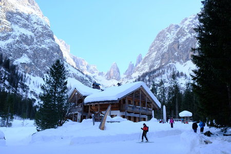 Sexten Dolomites, South Tyrol, Italy - circa February 2020: Rifugio Fondovalle in Val Fiscalina in Dolomites in beautiful snowy winter evening. Cross-country skiers are standing in front of shelter.のeditorial素材