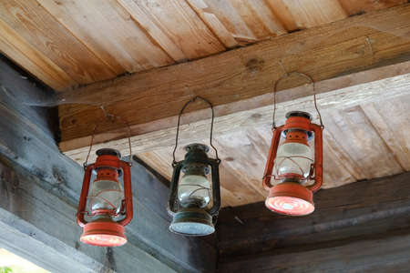 Three traditional kerosene lamps hanging under a wooden ceilingの写真素材