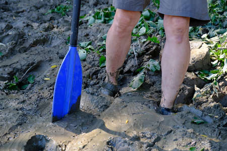 A man with an oar standing in the deep mud during the raftingの写真素材
