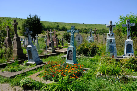 Koropets, Ukraine - circa July 2018: historic orthodox cemetery with blue crosses next to church