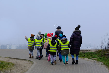 Gdansk, Poland - January 17, 2020: Group of preschoolers in reflective vests while walking on a foggy autumn day. Reflective vests increase safety on the road.のeditorial素材