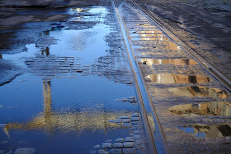 Old cobbled street and rails in puddles after rain. Reflection of buildings in water.の写真素材