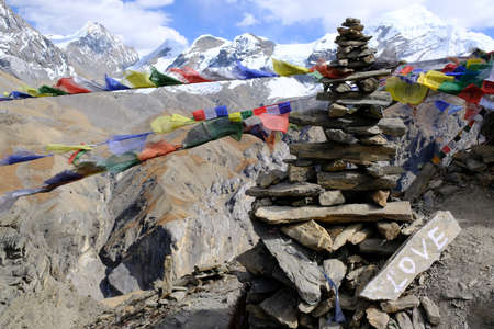 Stone stack with prayer flags and inscription "love" from viewpoint around High Camp, Thorong Phedi, Himalaya, Nepal. There is last lodge before Thorong La Pass. During trekking around Annapurna.の写真素材