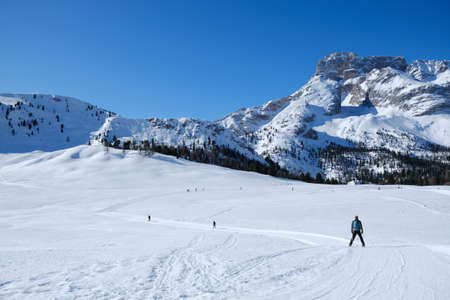 Beautiful winter mountain landscape with cross-country ski tracks and silhouette of running skiers....