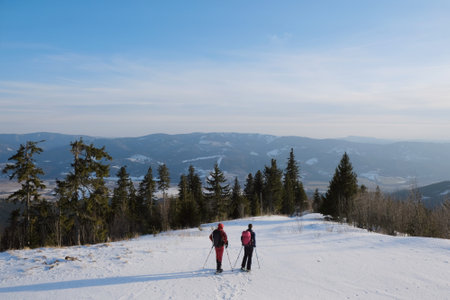 Winter mountain views on red ridge trail from Certovica - Sedlo za Lenivou - Sedlo Homolka during snowshoe tours in Low Tatras in Slovakia. Silhouettes of standing tourists on snowshoes.の写真素材