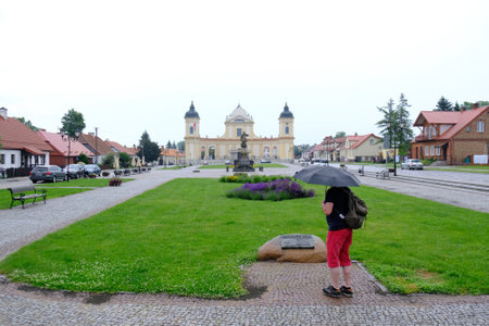 Tykocin, Podlasie, Poland - circa June 2020: Large Square with monument of Stefan Czarnecki and Church of St. Trinity. Silhouette of tourist man. Tykocin has historic buildings typical of Jewish town.のeditorial素材