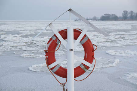 Lifebuoy on river covered with ice. Ice floe in shape of discs. An interesting phenomenon on Vistula river. The estuary of Vistula, Sobieszewska Island, Polandの写真素材