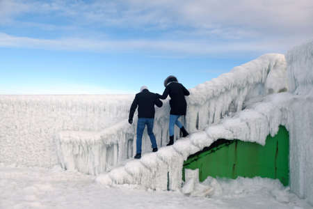 Silhouette of couple on very slippery stairs of amazing ice-covered lighthouse by Baltic Sea in Wladyslawowo, Kashubia, Polandの写真素材