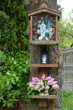 A roadside shrine with the Virgin Mary on a treeの写真素材