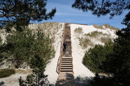 Silhouette of tourist on viewpoint with wooden footbridges nd stairs in "Lubiatowska Dune" nature trail on the Baltic Sea, Lubiatowo, Polandの写真素材