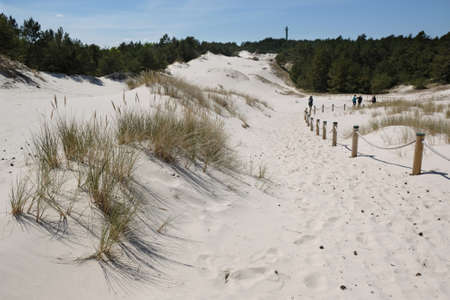 Silhouette of walking people in Lubiatowska Dune nature trail on the Baltic Sea, separation barriers...