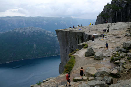 Preikestolen (Prekestolen, Pulpit Rock), Norway - circa July 2020: Famous tourist attraction near Stavanger. Preikestolen is steep cliff which rises above Lysefjord. Silhouettes of people on cliff.のeditorial素材
