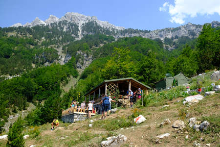 Albanian Alps, Albania - circa August 2021: Coffeehouse and silhouettes of tourists on trail from Theth Valley to Valbona Valley in Albanian Alps. It is one of the most beautiful high mountain trails.のeditorial素材