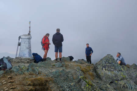 Albanian Alps, Albania - circa August 2021: Group of tourists on peak Djeravica (Gjerovica) - the highest peak of Kosovo. Mountain view above clouds. Peaks of Balkansのeditorial素材