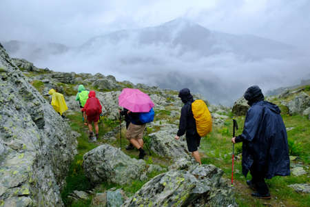 Group of tourists on mountain trail on rainy day. During trekking from DobÃ«rdol in Albania to the highest peak of Kosovo - Djeravica (Äeravica, Gjerovica). Albanian Alps, Peak of Balkansの写真素材