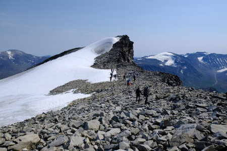 Beautiful mountain view of Jotunheimen National Park. Silhouettes of hiking people on trail to summit Galdhopiggen in snowy conditions. Norway, Scandinaviaの写真素材