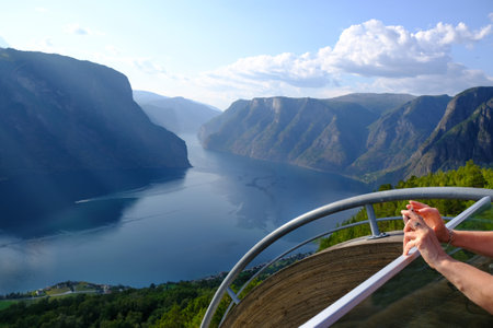 Close up of woman's hands, who is taking photo on viewing platform over Aurlandsfjord. Aurlandsfjord is one of most beautiful fjords in Norway.の写真素材