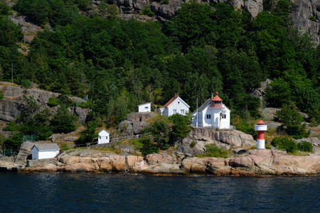 White buildings and little lighthouse by sea on coast of Aarhus, Denmark