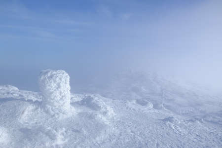 Frozen post marking a trail in Babia Gora massif on misty winter day. Diablak, Babiogorski National...
