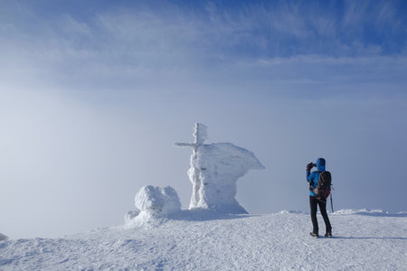 Man taking photo on Babia Gora Peak on winter misty day. Diablak, Beskid Zywieczki, Poland