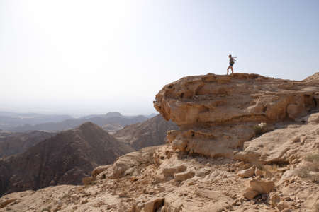 Silhouette of standing woman on rock at beautiful mountain viewpoint. Views of mountain range from...