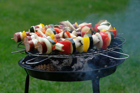 Close up of colorful skewers with sausage and vegetables on a garden grillの写真素材